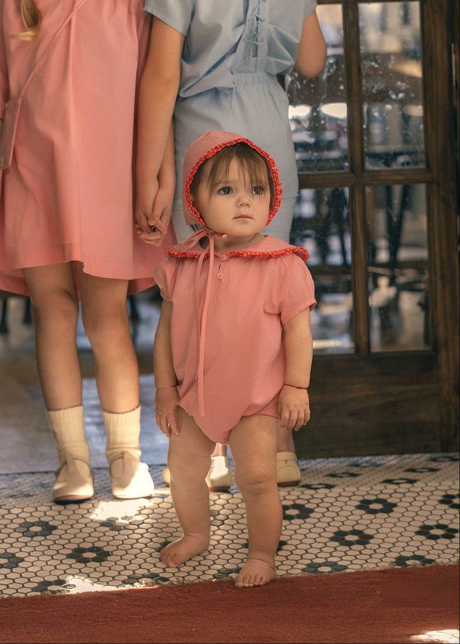 baby in pink romper with bonnet